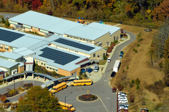 Roof of american school building covered with photovoltaic solar panels for production of electric energy. Renewable energy concept