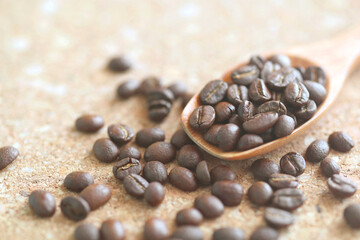 Roasted coffee bean with wooden coffee spoon on cork board, Close-up coffee beans