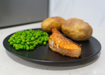 Healthy dinner plate with salmon peas and baked potatoes