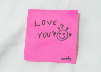 Handwritten love message on a pink post-it note