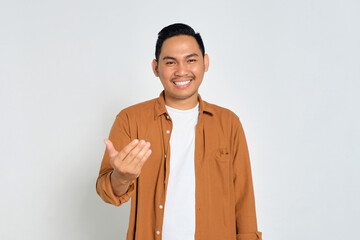 Happy young Asian man wearing casual shirt showing come on gesture with hands isolated on white...