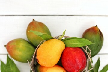Basket of mangoes, exotic fruits on white wooden table, top view, place for text, background