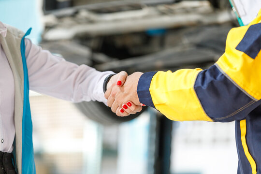 Close-up photo of a young artist shaking hands with female customers Complete vehicle inspection Satisfied customers in professional service garages
