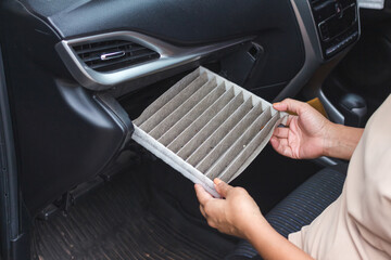 Women replacing cabin air conditioner filter of car.
