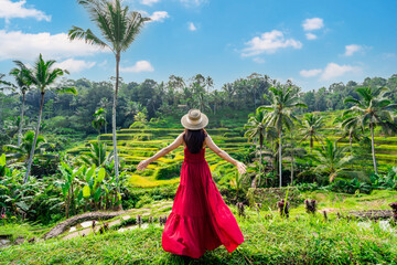 Young female tourist in red dress looking at the beautiful tegalalang rice terrace in Bali, Indonesia - 631376324