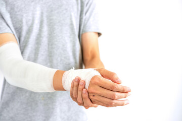 Young man with gauze bandage wrapped around injury hand on white background