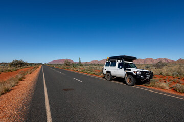 Endless stretch of road in Central Australia with range of hills in the background