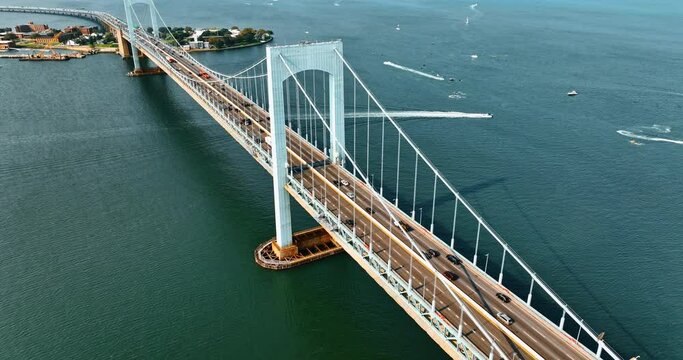 Cars going to and from the Bronx, New York. Aerial view of the Throgs Neck Bridge on sunny day. Boats sailing on the East River at backdrop.