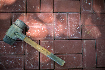 A hammer with rubber tips used in paving works lies on the paving stones.