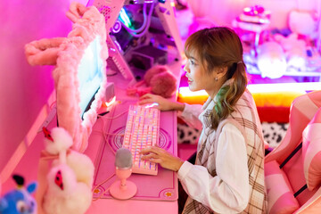 Young Asian woman Esports player playing online game on computer in bedroom. Attractive girl vlogger influencer gamer enjoy and fun live streaming broadcast games challenge on social media platform. © CandyRetriever 