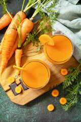 Naklejka na ściany i meble Carrot healthy juice for detox. Carrot juice in a glass and fresh carrots with leaves on a stone table. Healthy vegan vegetarian drink. View from above.