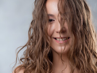 Obraz premium Portrait of a young beautiful woman with wet curls. Close-up on a light background.
