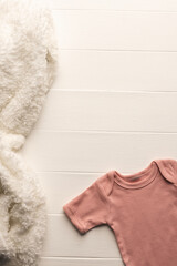 Flat lay of pink baby grow and fur rug with copy space on white board background