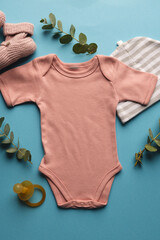 Flat lay of pink baby grow, hat, dummy and pink booties with copy space on blue background