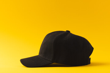 Black baseball cap and copy space on yellow background