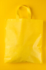 Close up of yellow canvas bag with copy space on yellow background
