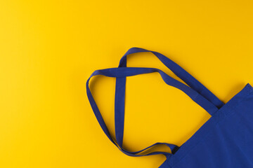 Close up of blue canvas bag with copy space on yellow background