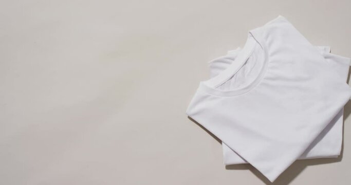 Video of stack of folded white t shirts with copy space on white background