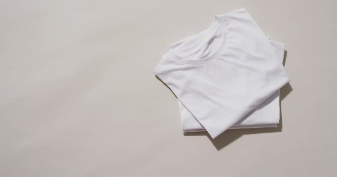 Video of stack of folded white t shirts with copy space on white background