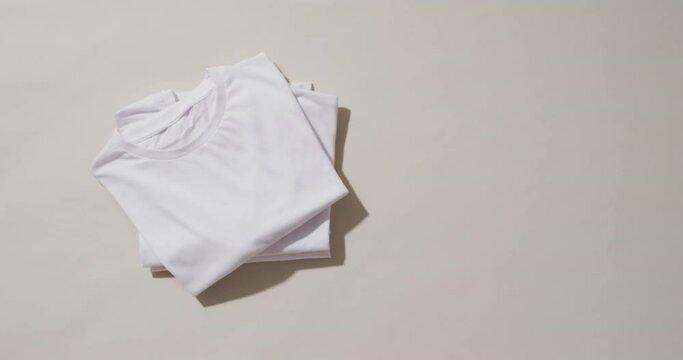 Video of stack of folded white t shirts with copy space on white background