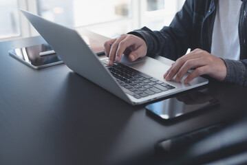 Business man working on laptop computer keyboard and surfing the internet on office table, online working, business and technology, internet network communication concept, close up