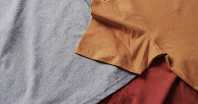 Video of flat lay of multi coloured t shirts with copy space on white background