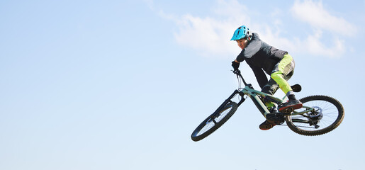 Obraz premium Mountain bike, man and jump in blue sky for competition, freedom or adventure on mockup space. Banner of athlete, sports and bicycle in air for action, cardio race and courage of stunt, speed or risk