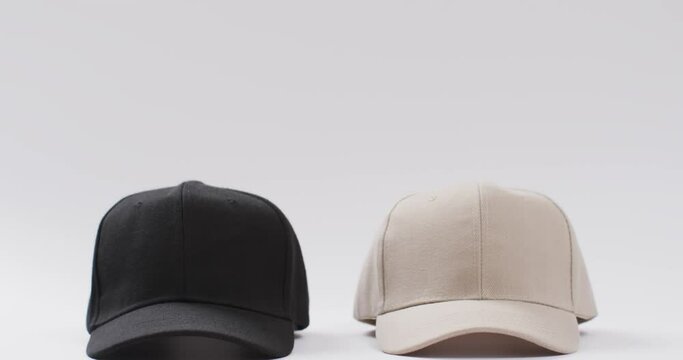 Video of black and beige baseball caps and copy space on white background