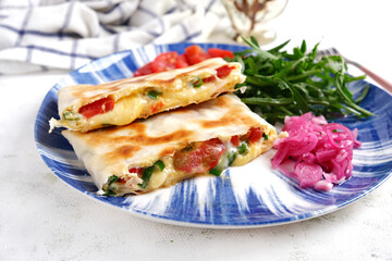 Tasty breakfast with quesadilla and eggs. Mexican cuisine. Trending food with pita bread, omelet, cheese, tomatoes