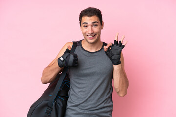 Young sport caucasian man with sport bag isolated on pink background showing ok sign and thumb up...
