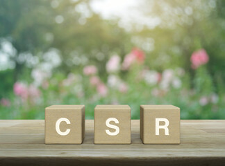 CSR letter on wood block cubes on wooden table over blur pink flower and tree in park, Corporate...