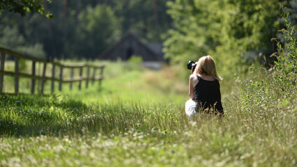 girl photographer photographing nature, sitting in woods, back view. young woman in spring forest....