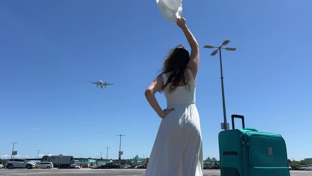 Plane spotting. Thrill seeking tourists wait for low flying aircraft to land on the runway. lady in a dress and hat stands waving to the passengers as they arrive at their holiday destination.