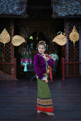 Fototapeta premium Pretty Asian woman wearing ancient native Thai traditional dress costumes standing in the classic Thai house.