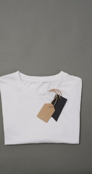 Vertical video of white t shirt with tags and copy space on grey background