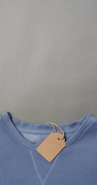 Vertical video of blue t shirt with tag and copy space on grey background