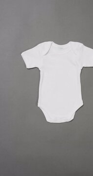 Vertical video of white baby grow and copy space on grey background