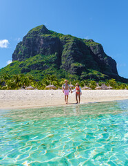 Man and Woman on a tropical beach in Mauritius, a couple on a honeymoon vacation in Mauritius Le Morne Beach with Le Morne Mountain on the background with a blue sky - obrazy, fototapety, plakaty