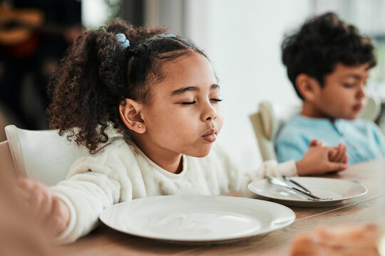 Kids, holding hands and praying at dinner, home and faith for gratitude, solidarity and mindfulness for food. Children, prayer and religion for event, lunch or brunch with eyes closed in family house