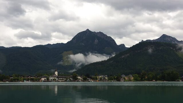 Time lapse fog created above Strobl village in Alp mountain. Overcast weather in hill valley, Wolgangsee Austria
