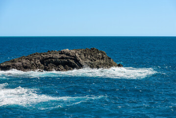 Cliff and Mediterranean Sea with white waves in front of the small village of Framura, La Spezia province, Liguria, Italy, Europe.