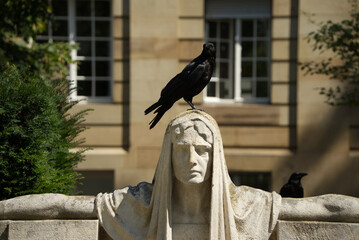 Statue of the goddess of fate in Stuttgart with a raven on her head