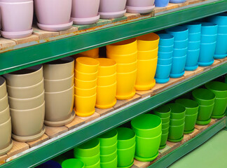 Empty flower pots in a store or greenhouse. Ceramic or plastic flower pots at the shop. Colorful flower pots on the shelf in the store.