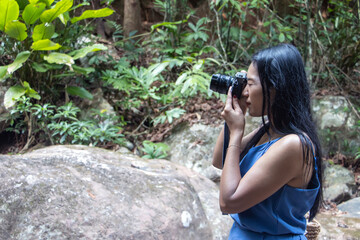 A young woman with a camera takes a photo in nature