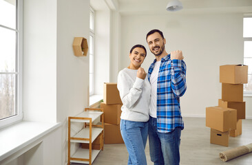 Fototapeta na wymiar Happy couple in love moving in new home. Joyful loving spouses posing in new apartment celebrating moving day. Home relocation, family housing, real estate, mortgage