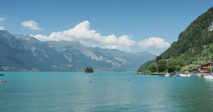 The Bay of Iseltwald facing Lake Brienz in Switzerland. Small marina and its nautical activities, swimming on calm waters facing Turtle Island (Schneckeninsel)
