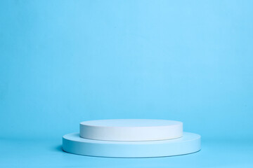 Round white platform podium on pastel blue background. Podium to show cosmetic products.