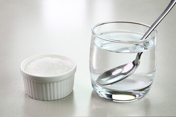 Mixing sugar in a cup of water.