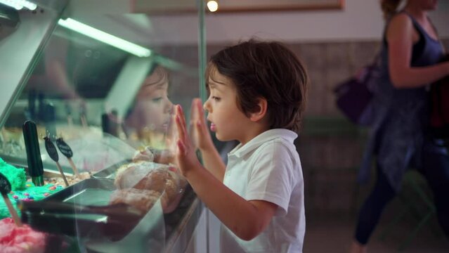 Child Leaning on Ice-Cream Glass Counter, Staring at Flavors, Childhood Concept of salivating Dessert
