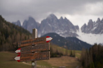 Wooden signpost in front of rough Alpine mountain range in the background. Hiking Adventures in the Majestic Dolomites. Exploring Nature's Beauty